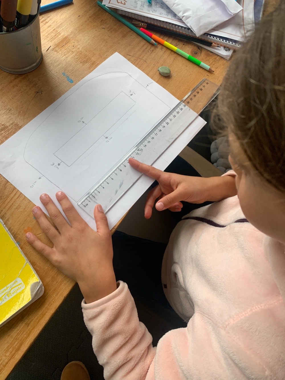 A child measuring and drawing a plan with a ruler